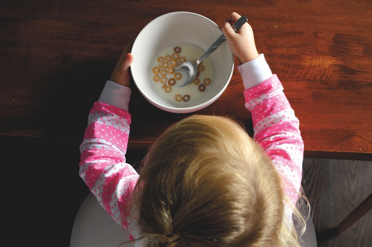 girl holding a bowl of milk and cereal